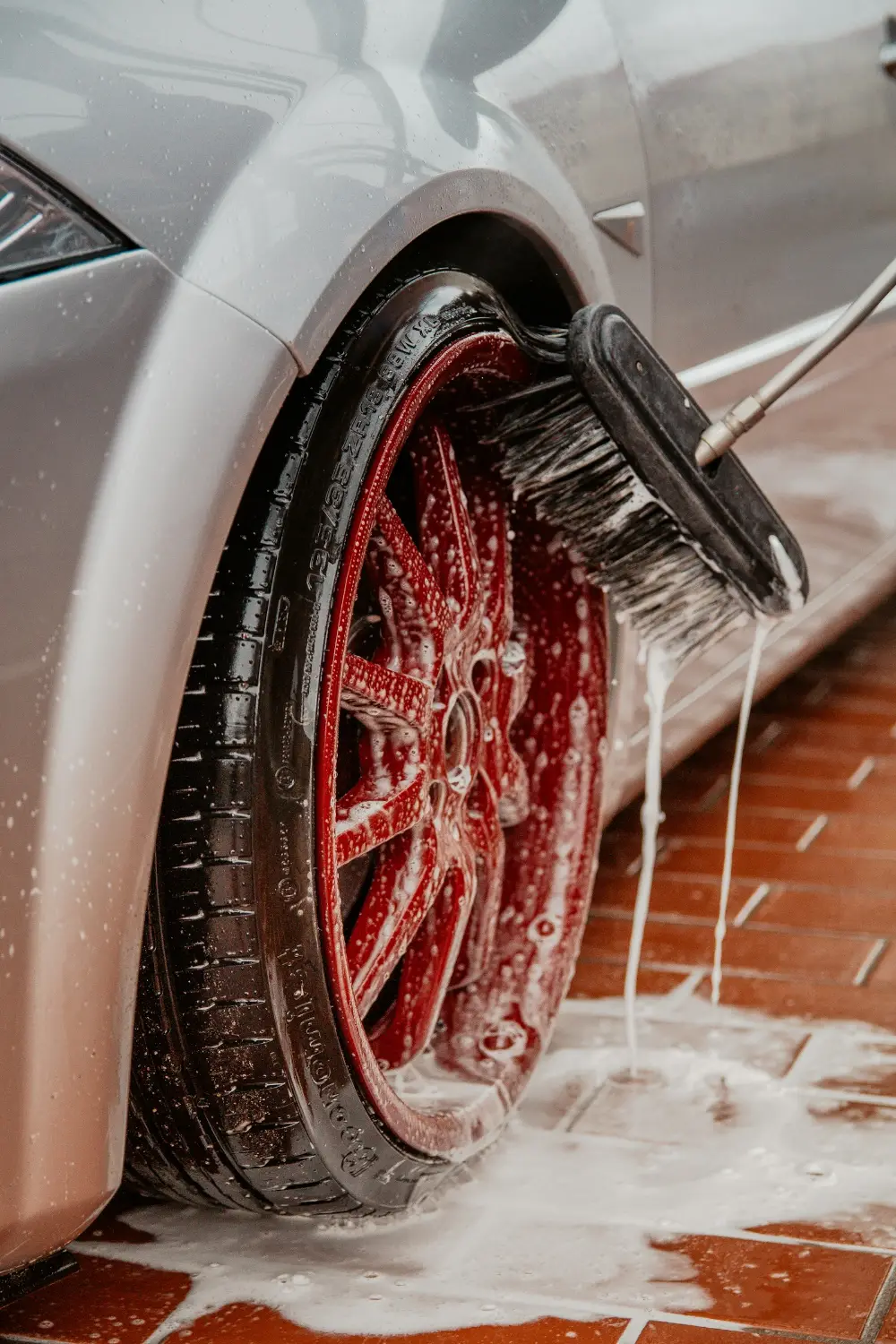 Brush cleaning a red alloy wheel
