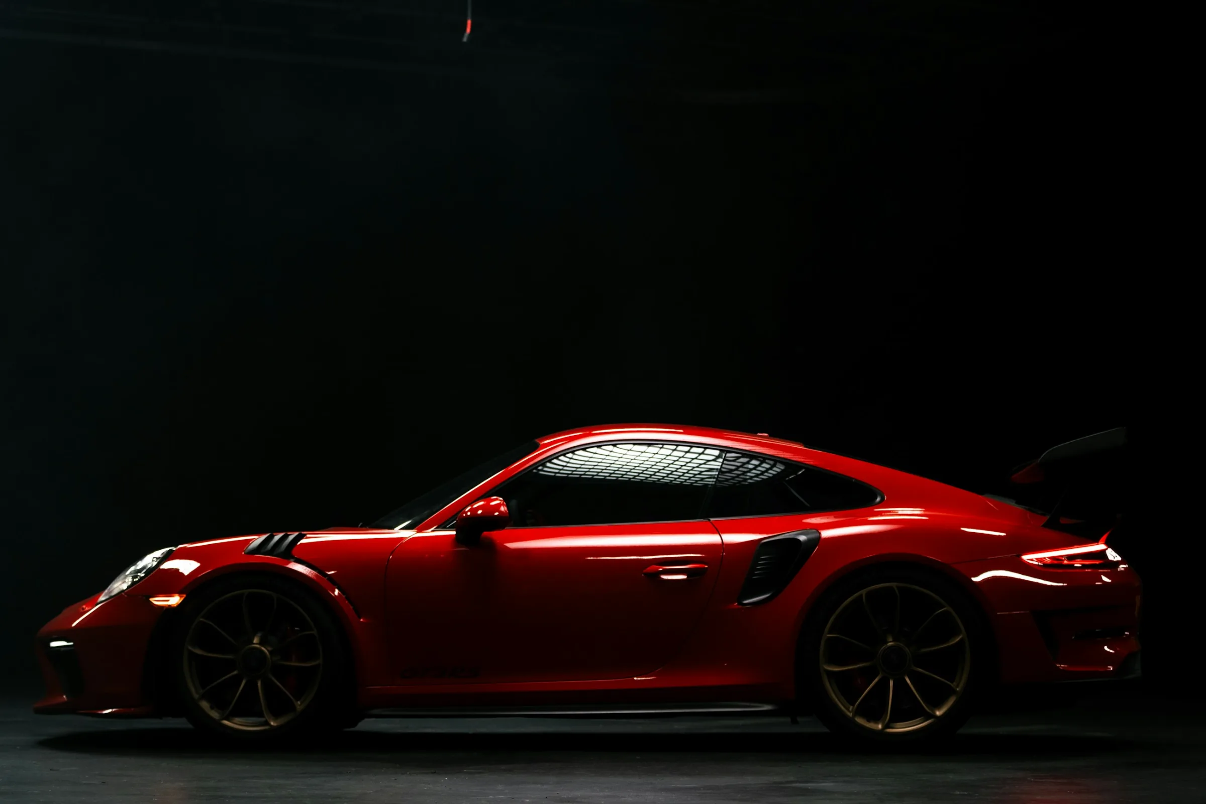 Red sports car glowing in a dark studio